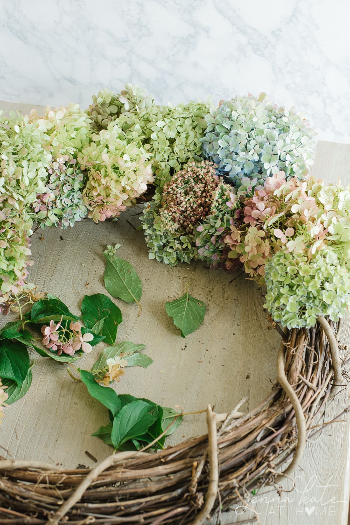 A mixture of fresh and dried hydrangeas in different varieties and colors form the fall DIY wreath