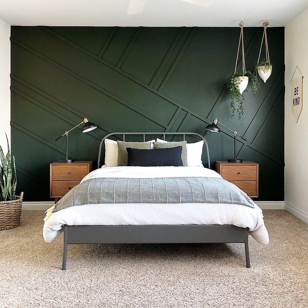 Bedroom with a dark green accent wall, hanging plants, natural wood side tables and a bed