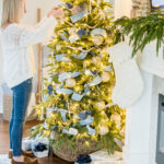 A person adding ribbon to a Christmas tree