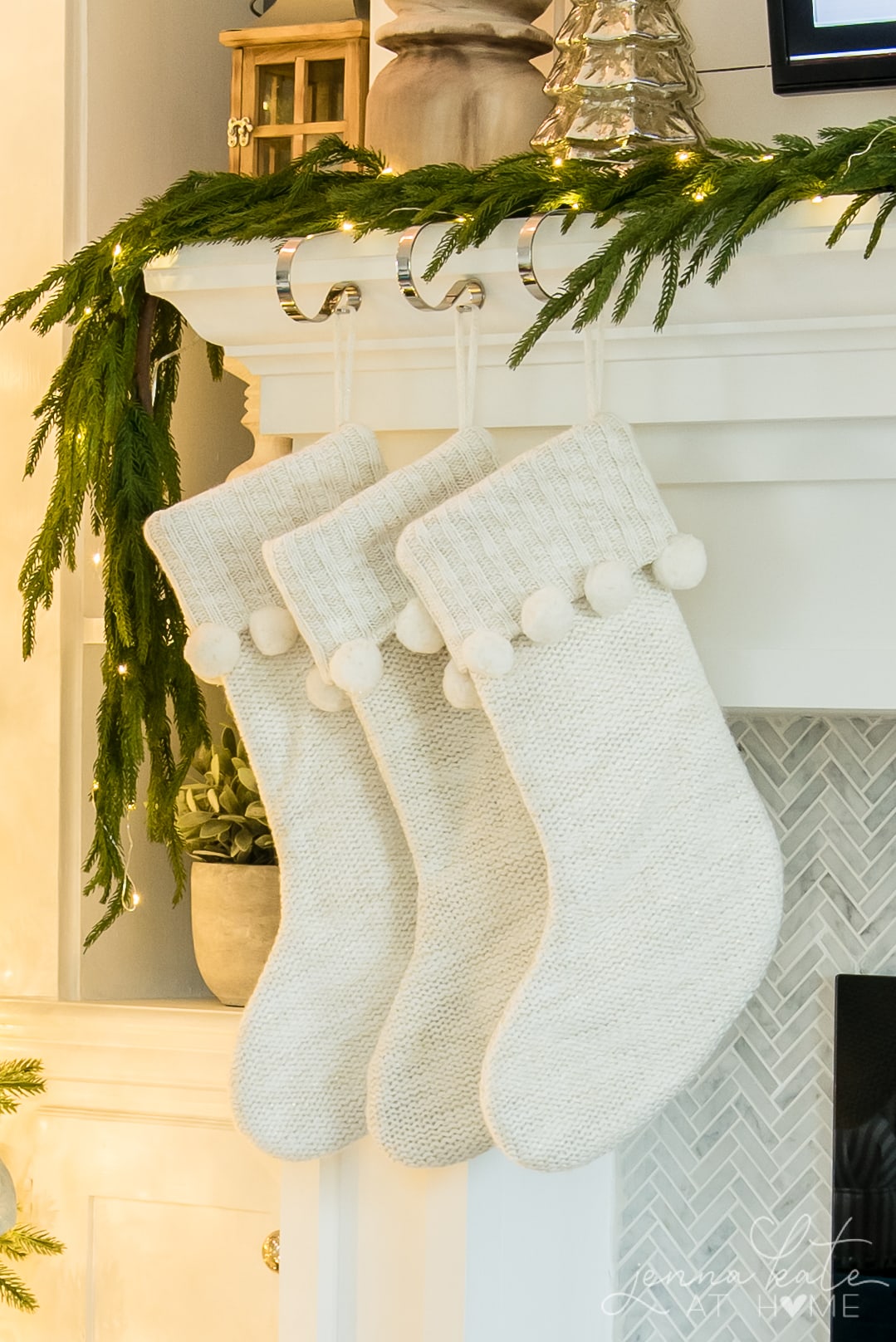 White knit stockings with pom poms hung on the mantel