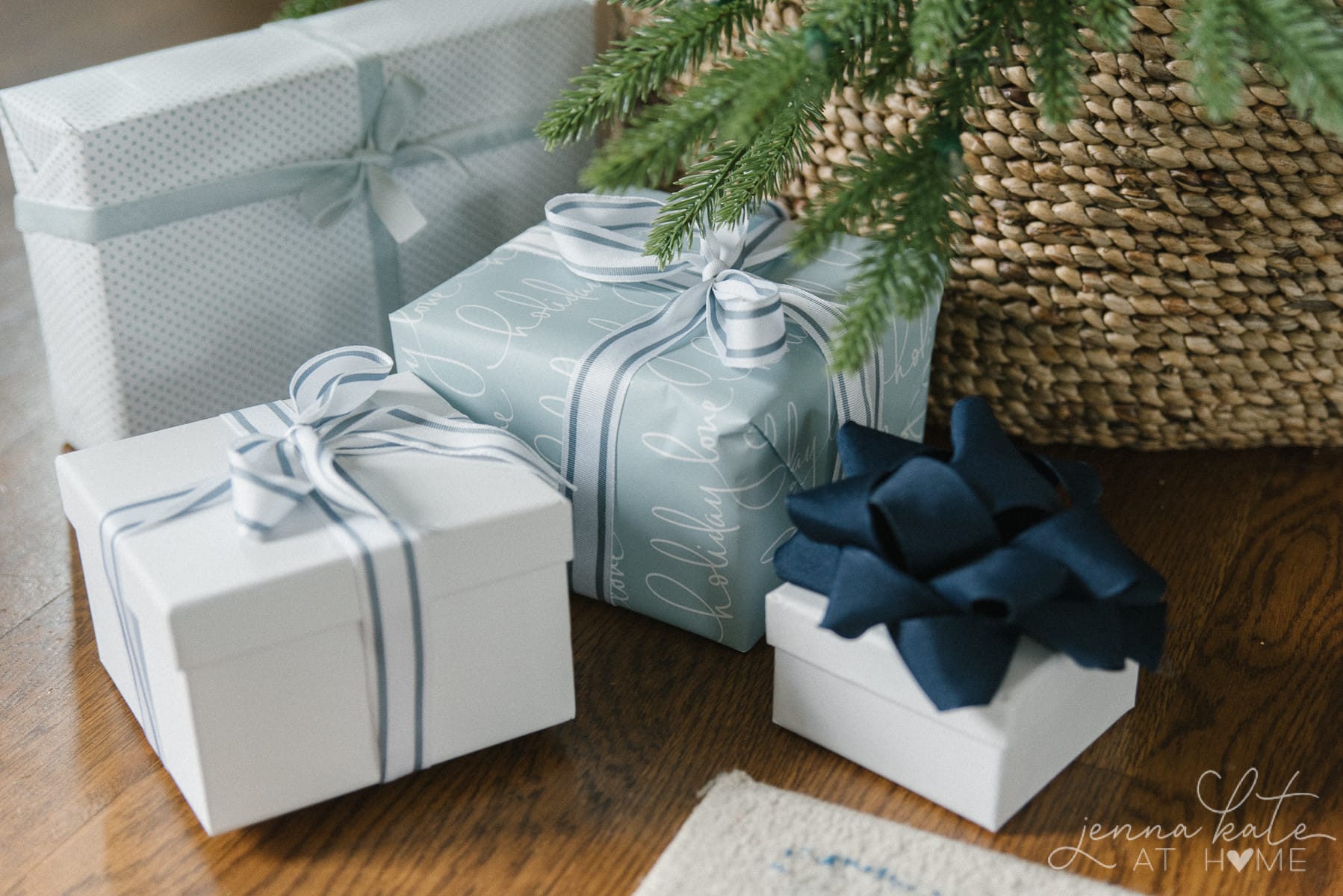 Matching blue ribbon and wrapping paper on gifts below Christmas tree