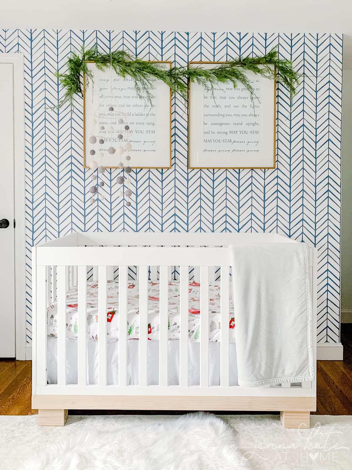 Nursery with blue wallpaper and garland hanging on the picture frames over the crib