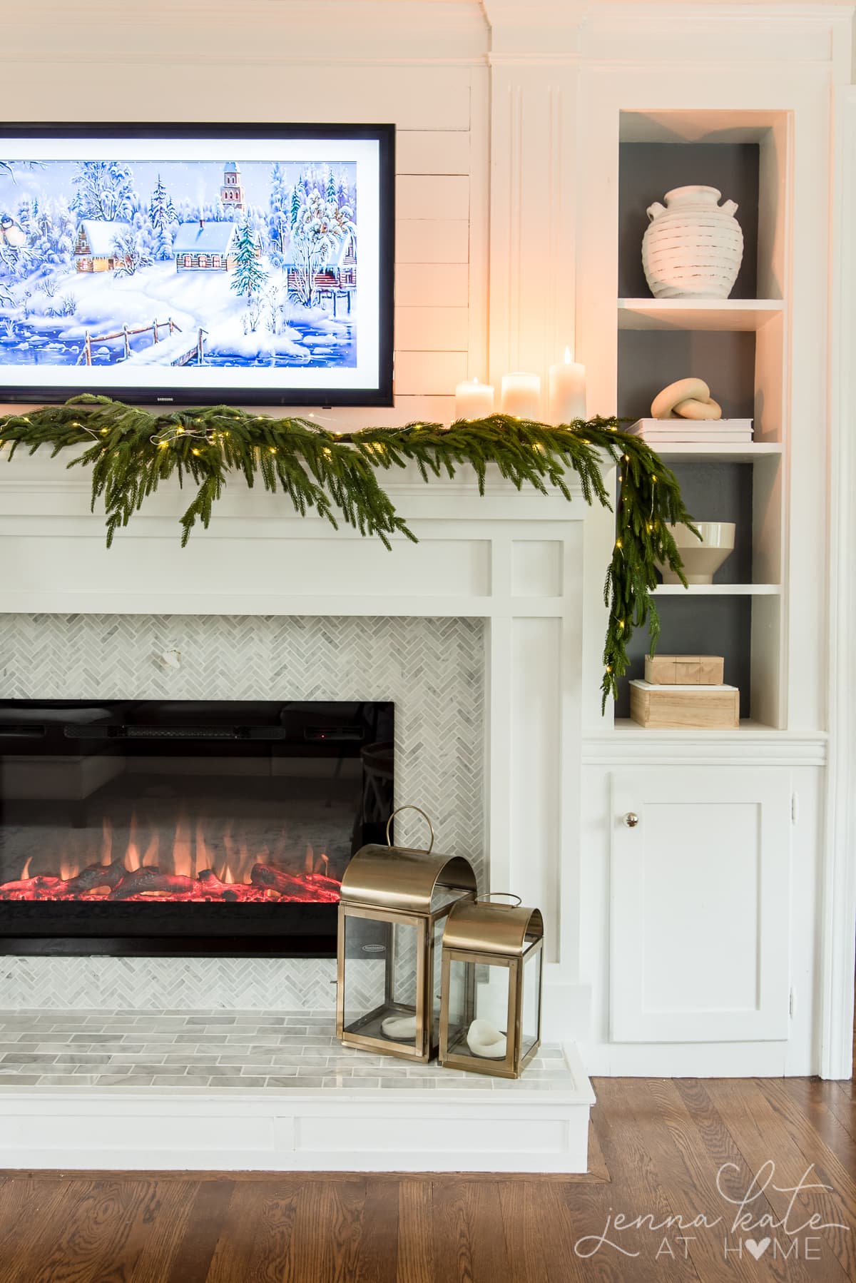 Pillar candles on a mantel surround by faux greenery