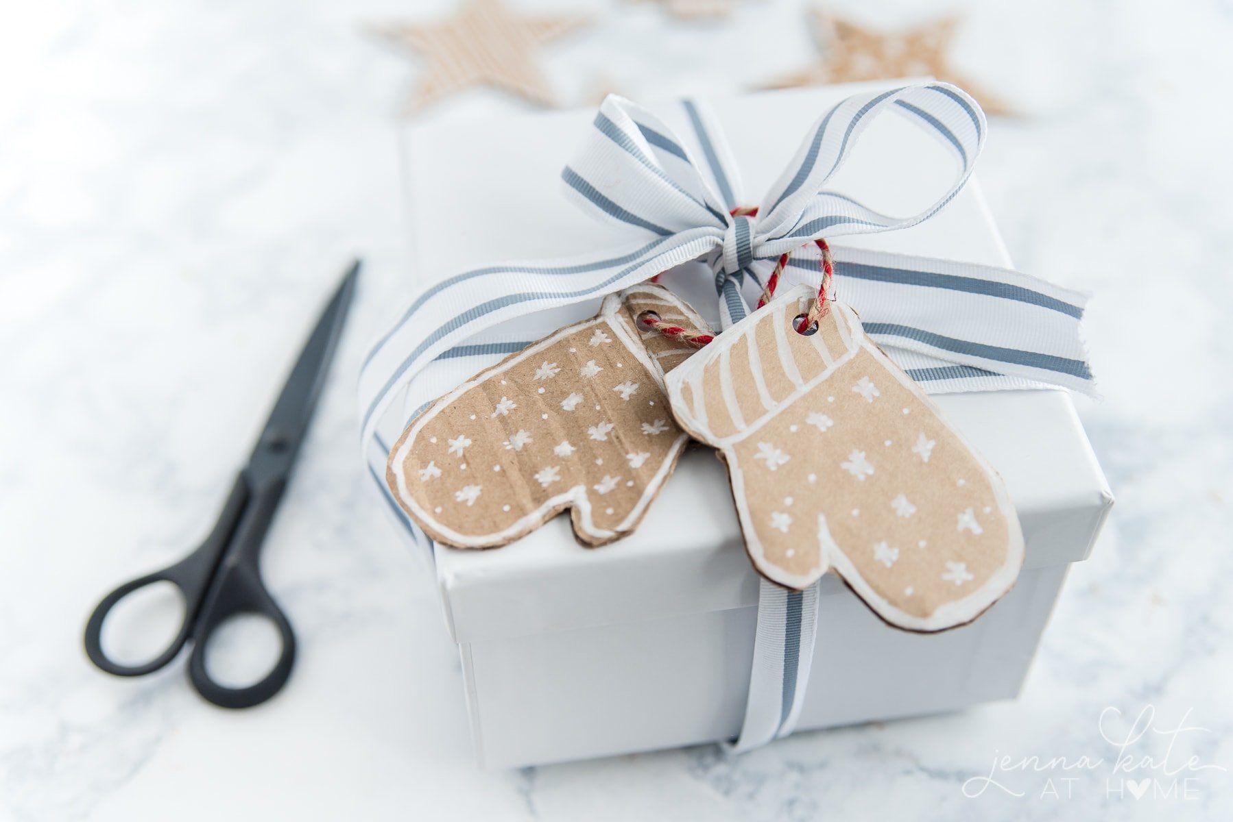 cardboard mitten gift tags hung on a white gift box