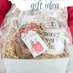 A basket with hot chocolate, mugs, and chocolates that a women is holding as a gift.