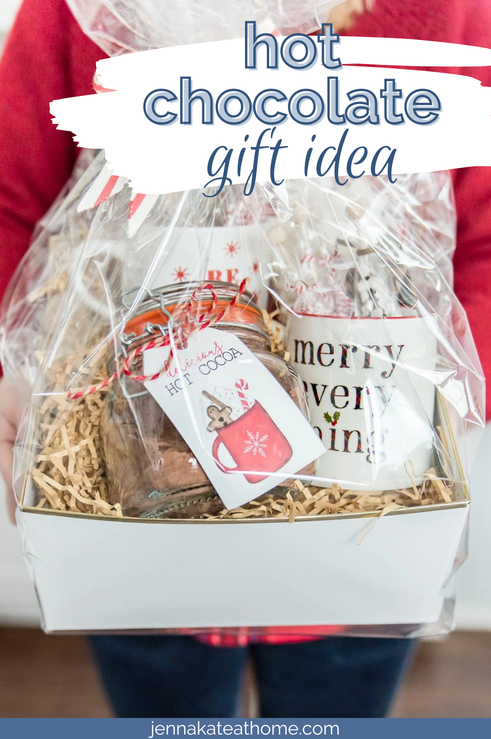 A basket with hot chocolate, mugs, and chocolates that a women is holding as a gift.