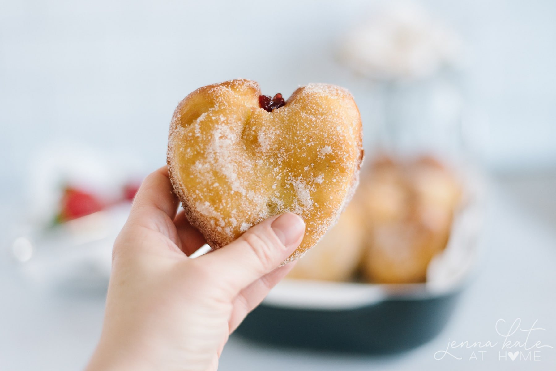 Hand holding up a heart shaped yeast donut