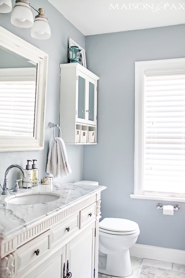 bright bathroom with marble topped vanity and blue-gray walls