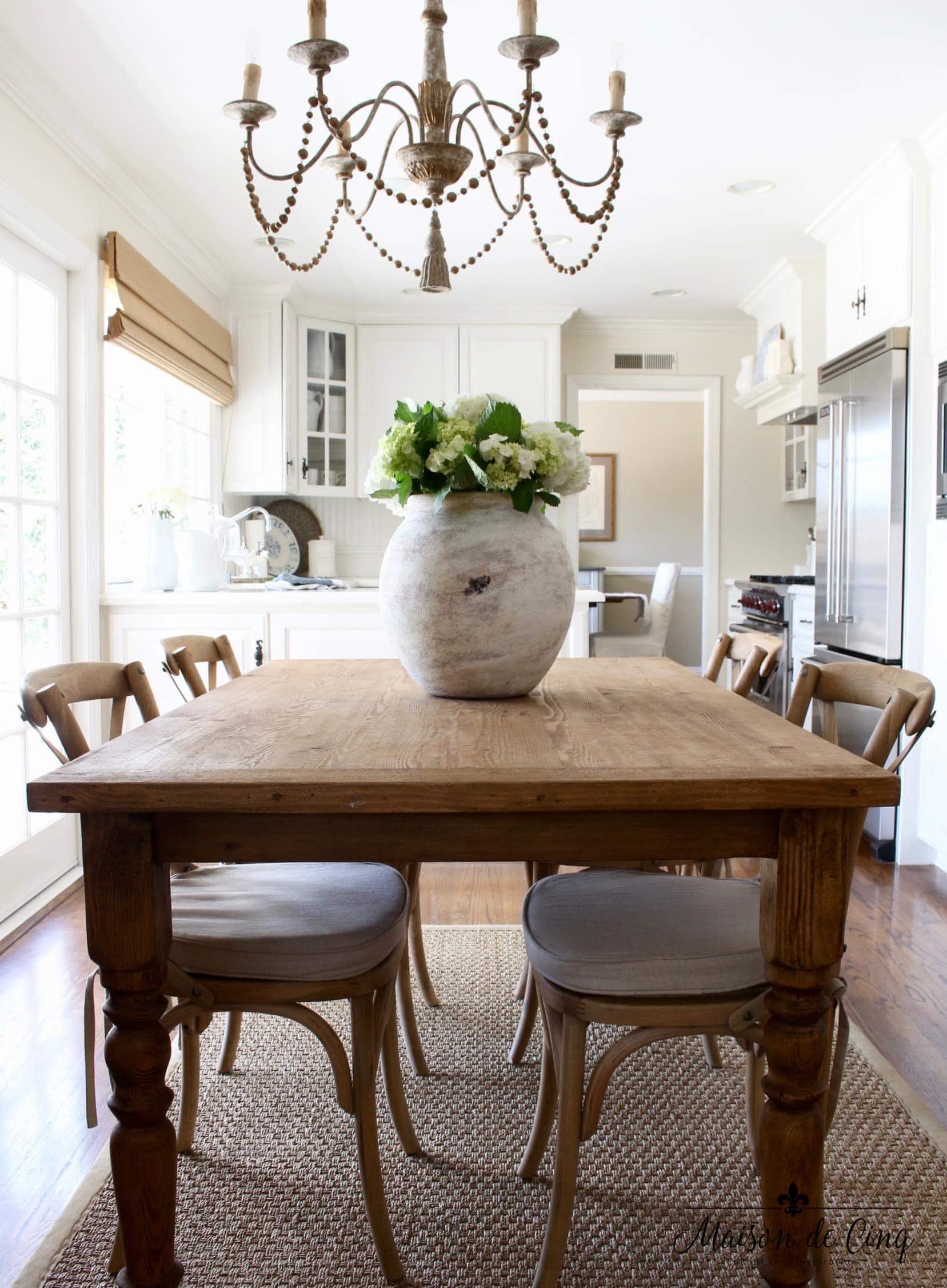 farmhouse table in the kitchen nook with  a large urn full of hydrangeas