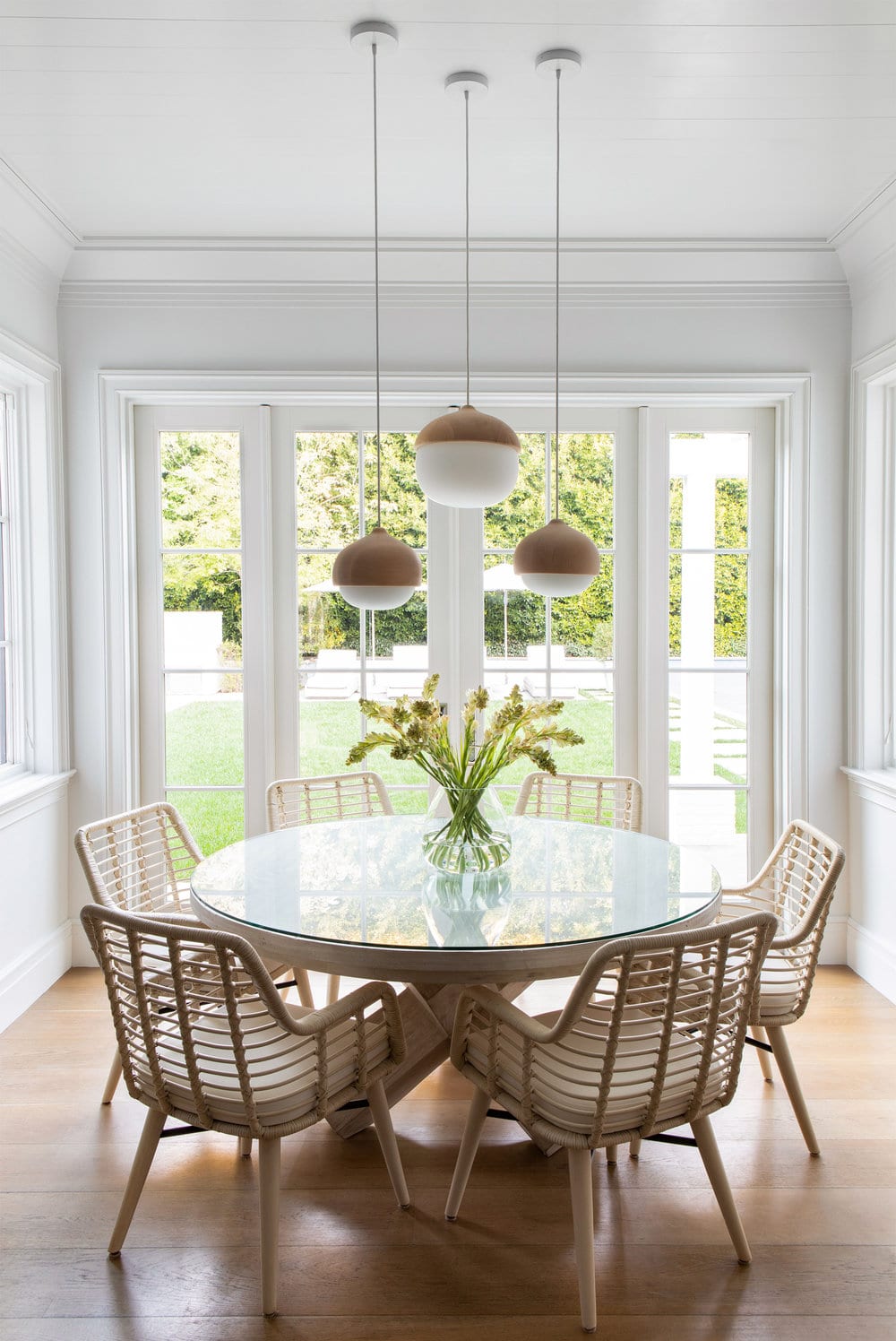 round pedestal table with rattan chairs and modern light fixture