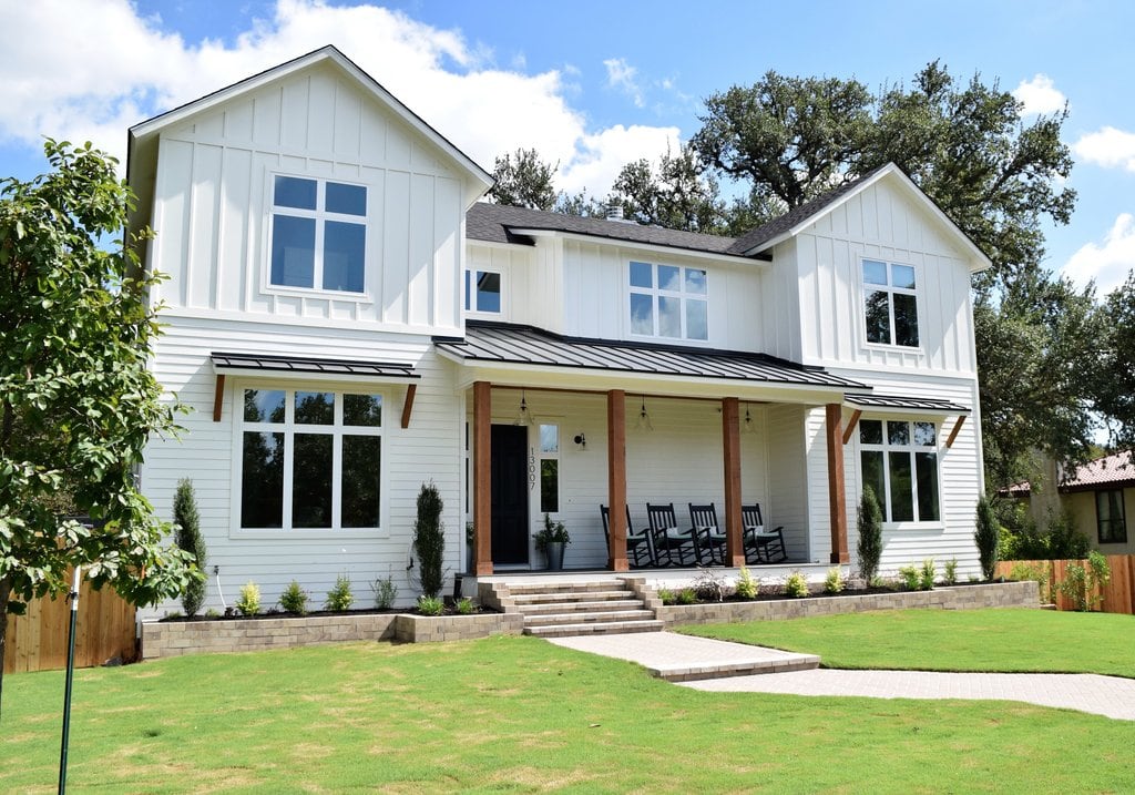 white farmhouse with cedar posts and a green lawn