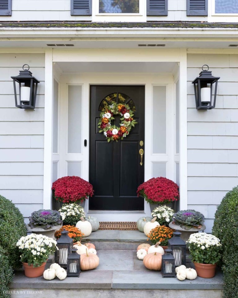 Mums and pumpkins on the front steps of a house