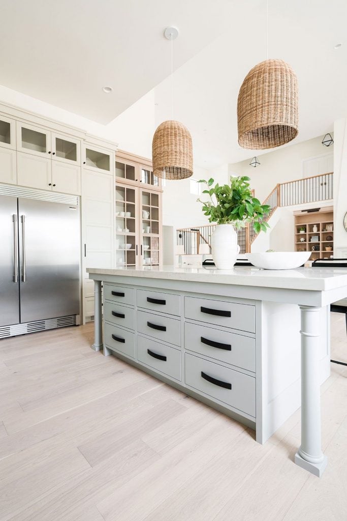 light gray blue kitchen island with rattan pendant lights overhead