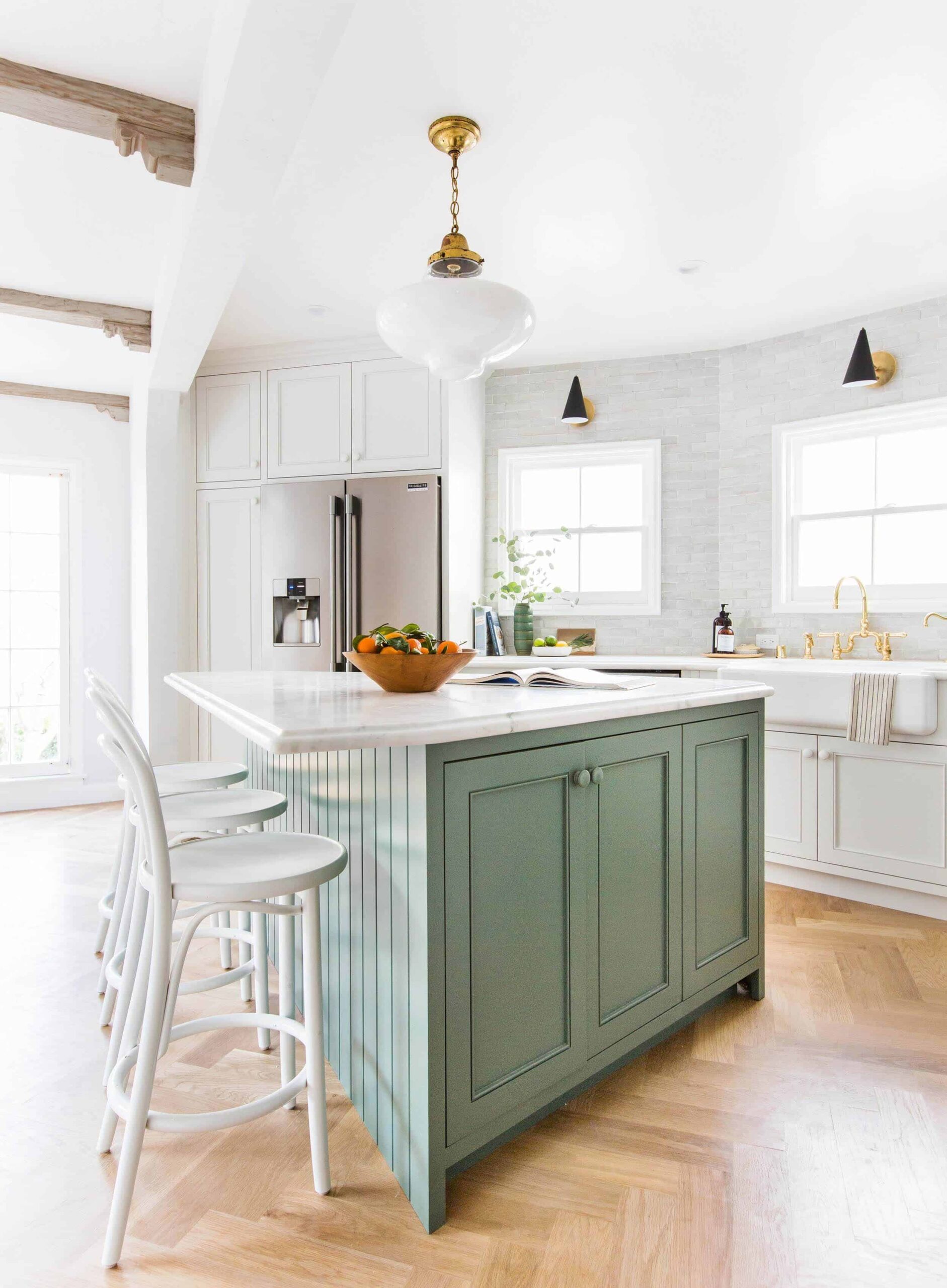 green kitchen island with white stools and farmhouse style accents