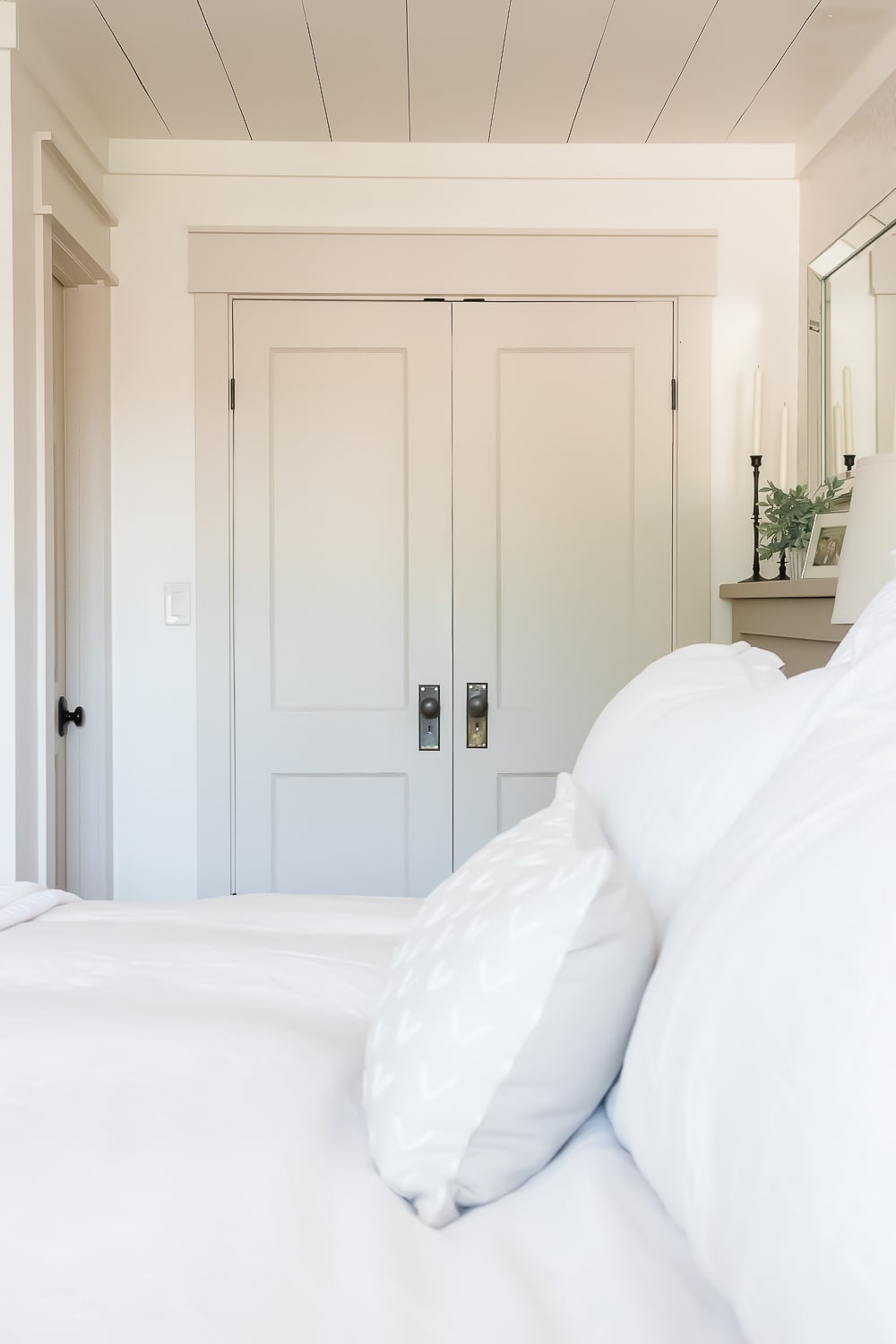 Close up of interior doors painted Benjamin Moore Edgecomb Gray with bright white sheets and pillows on the bed. 