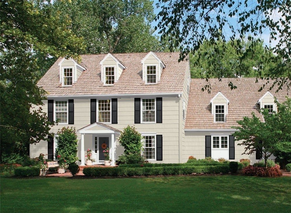 Large Colonial style house with Benjamin Moore Edgecomb Gray siding with beautifully landscaped front yard.
