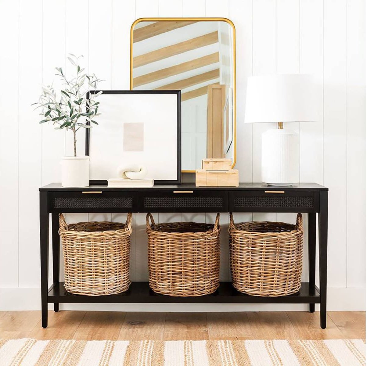 black console table with layered mirror, artwork and table lamp