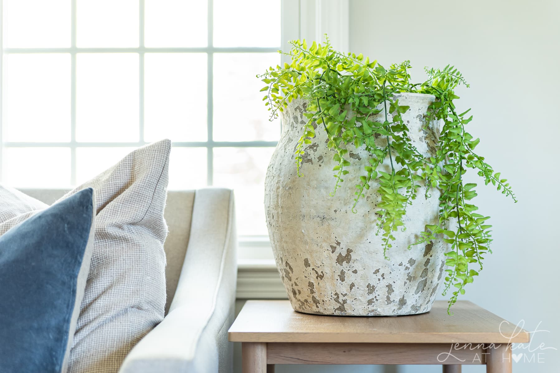 living room side table with a large oversized vase with trailing green plant