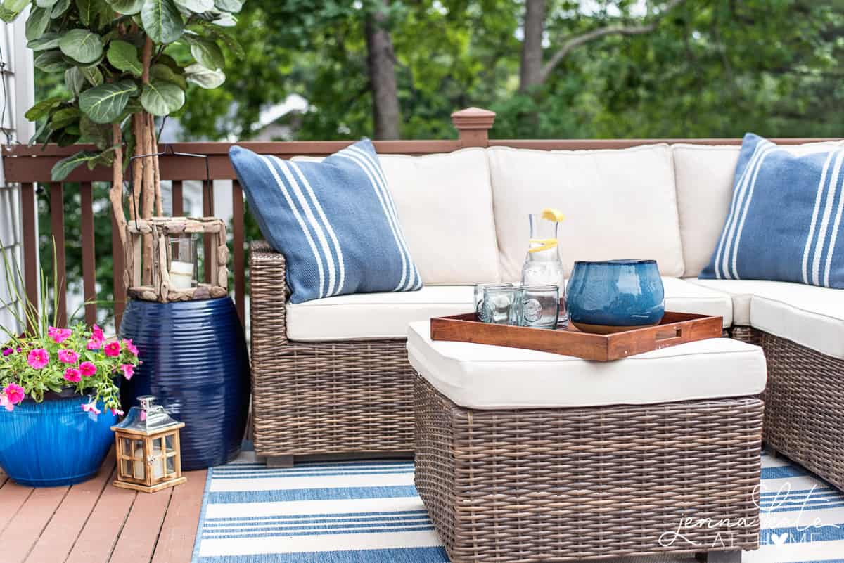 Deck decorated for summer with a sectional with blue throw pillows