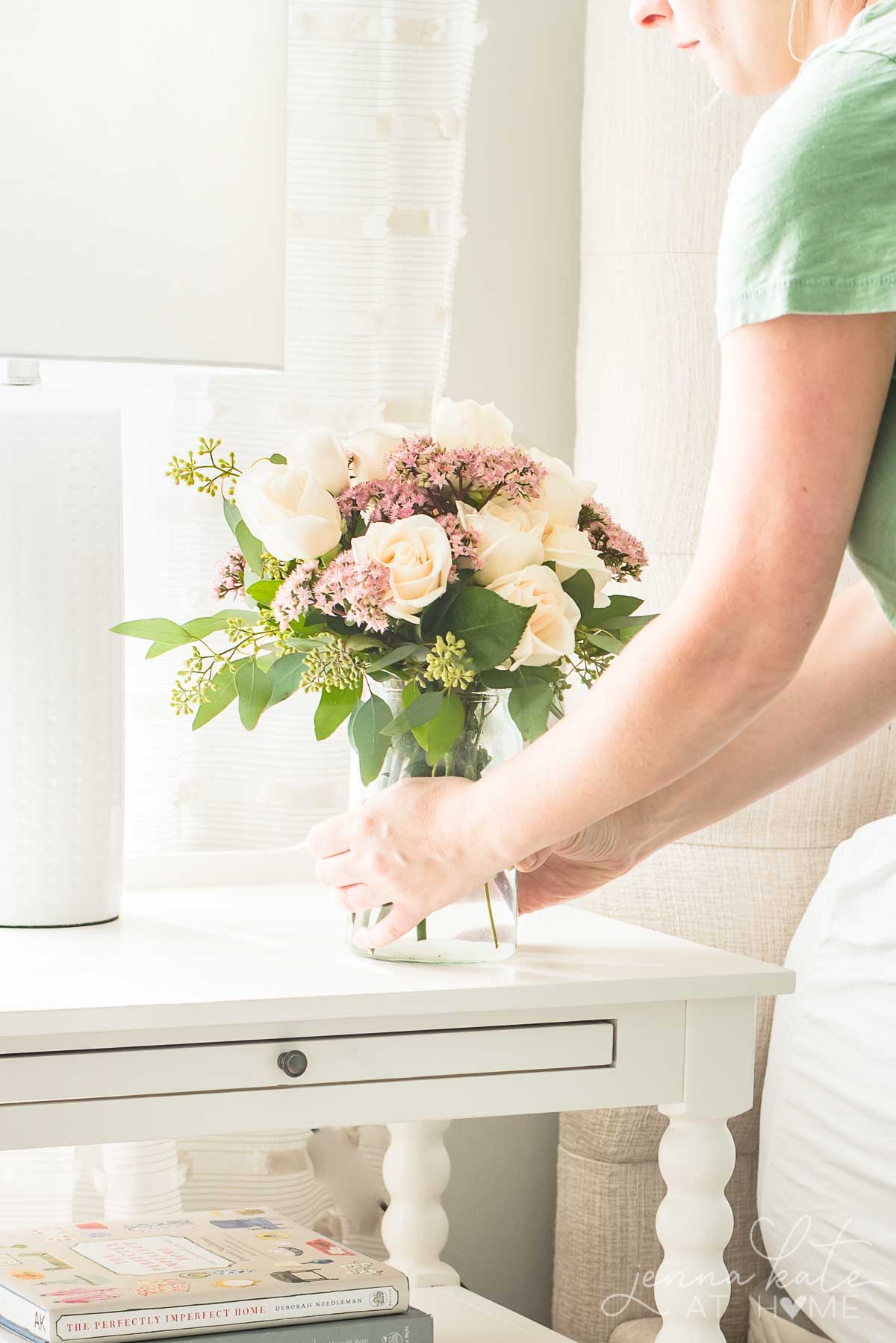 bedroom nightstand with woman placing vase of summery flowers on it