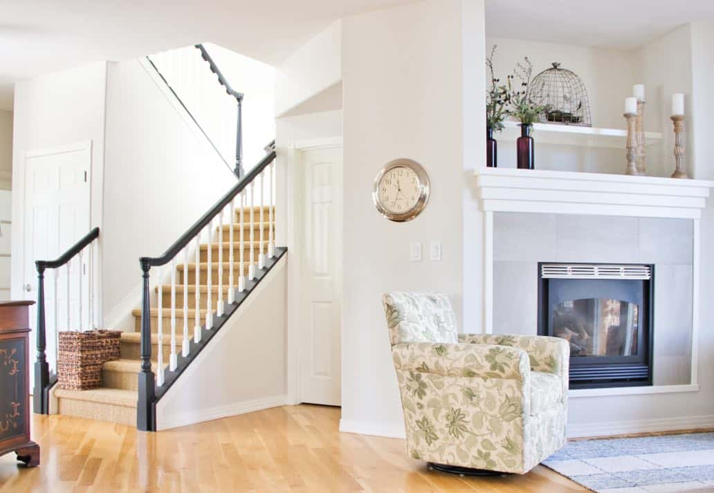 living room open to foyer with warm oak floors and staircase with black railings