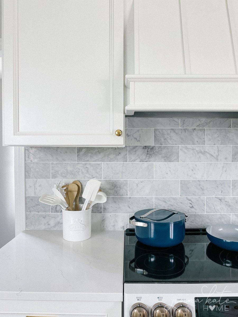 white quartz counter tops, marble backsplash and white cabinets