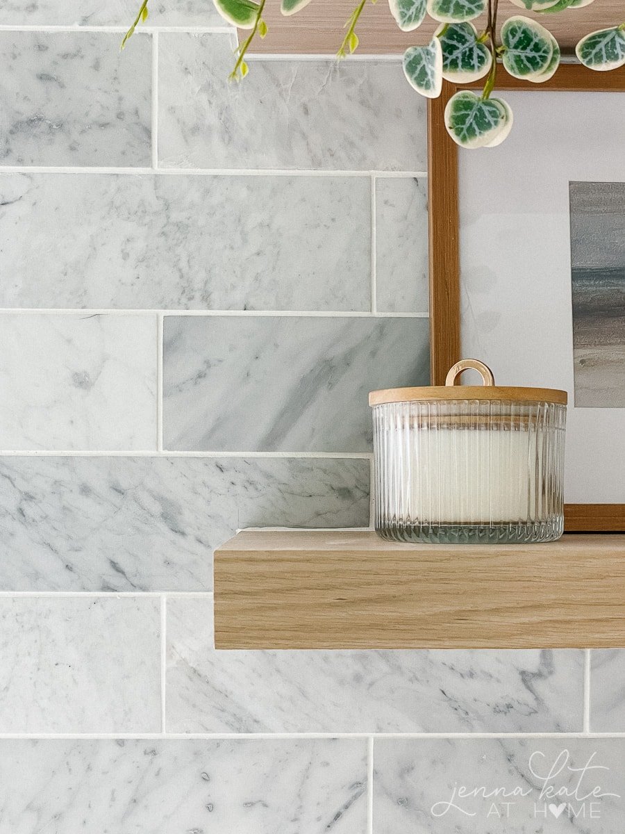 carrara marble backsplash and oak floating shelf