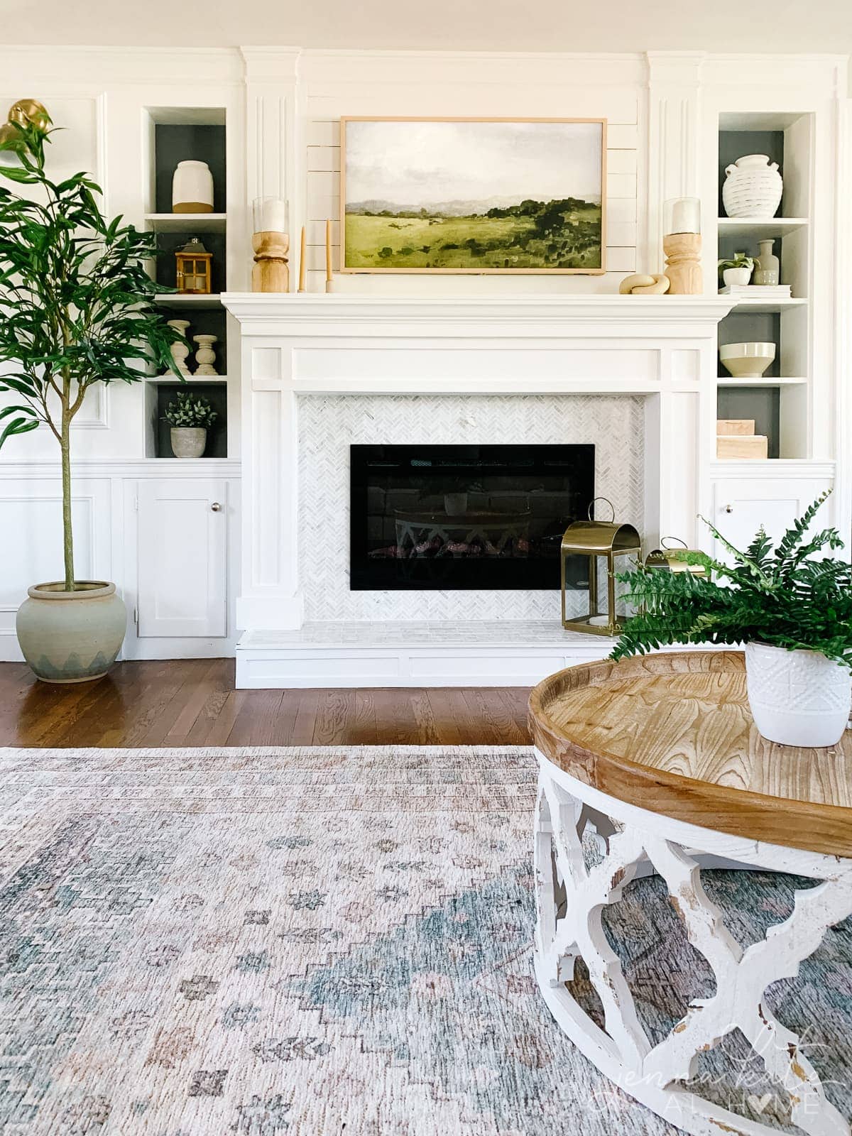 white fireplace and narrow built-ins with a ficus tree on one side and Frame TV over the fireplace