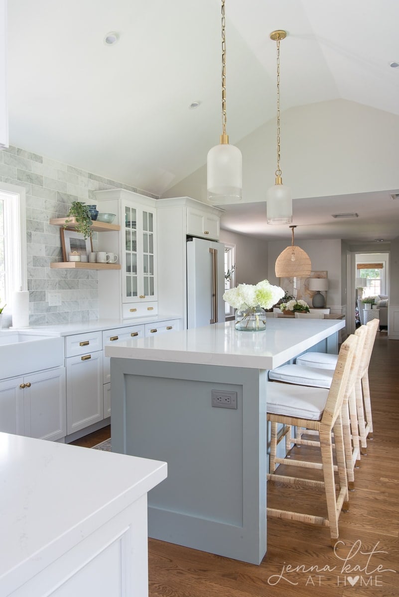 white kitchen with a blue island and statement glass pendants.