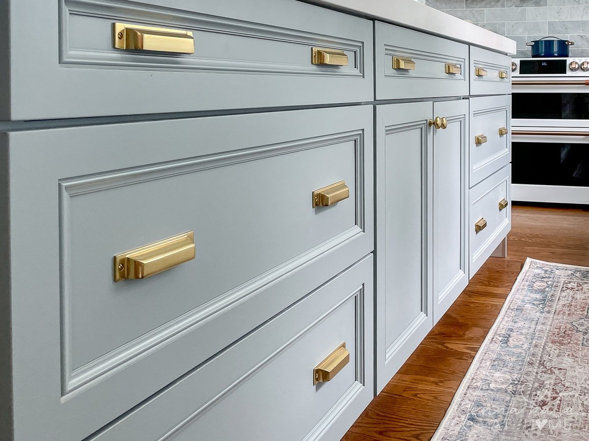 kitchen island painted a blue gray color with brass hardware