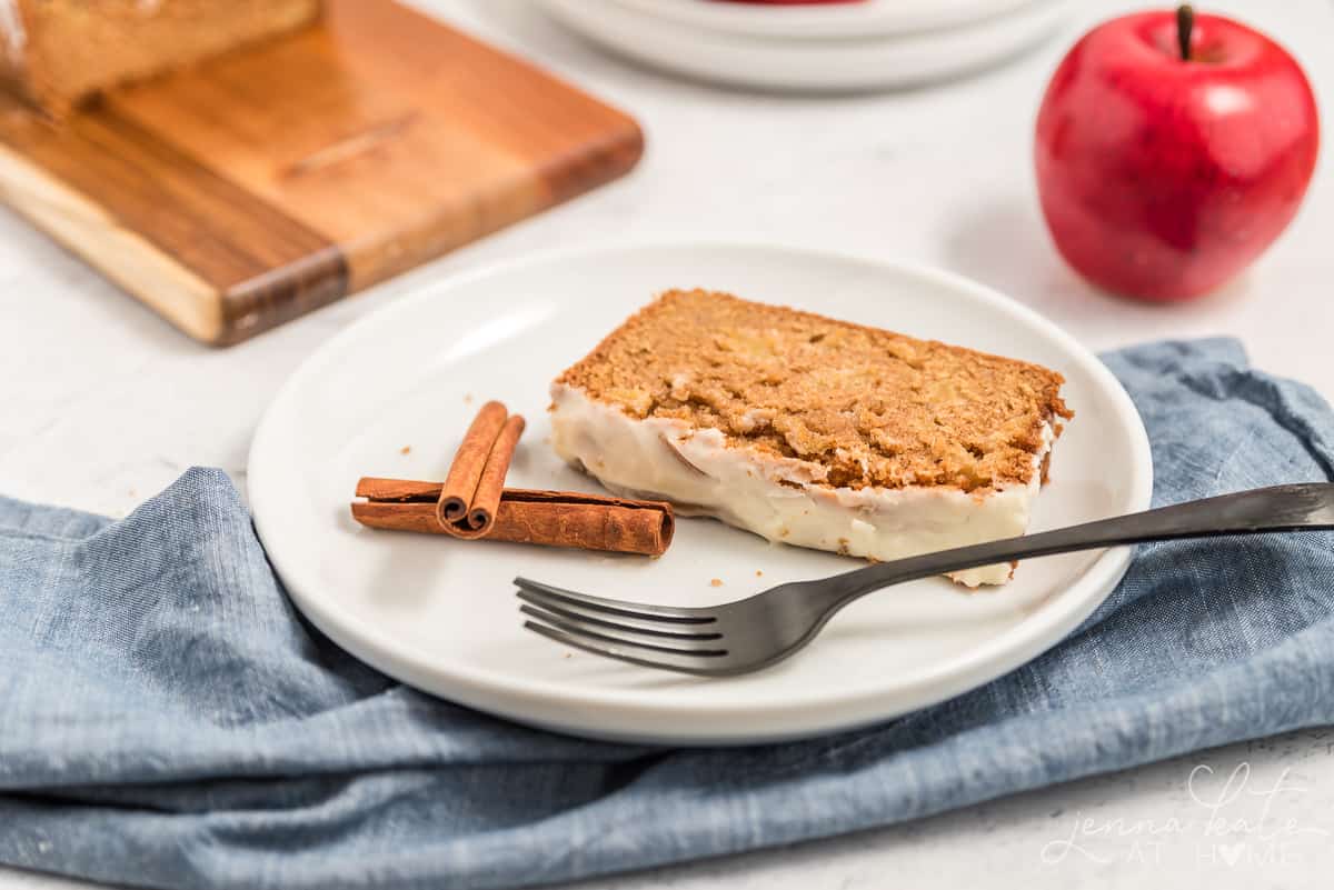 slice of apple bread on a plate with a fork and some cinnamon sticks