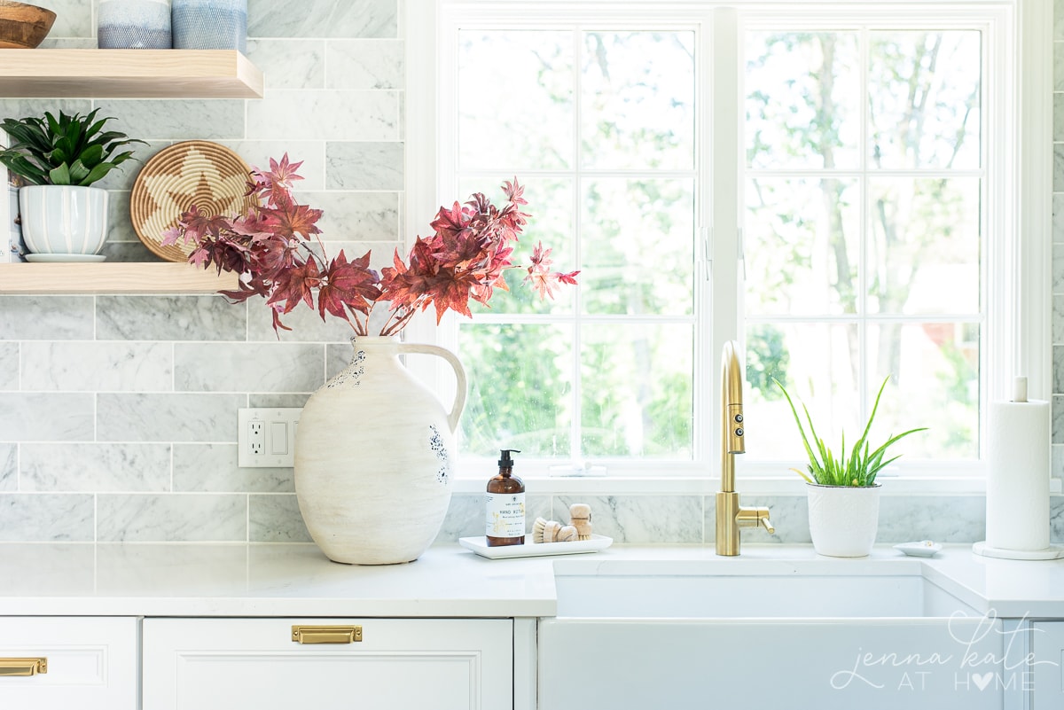 vase of Japanese maple branches on a kitchen counter.