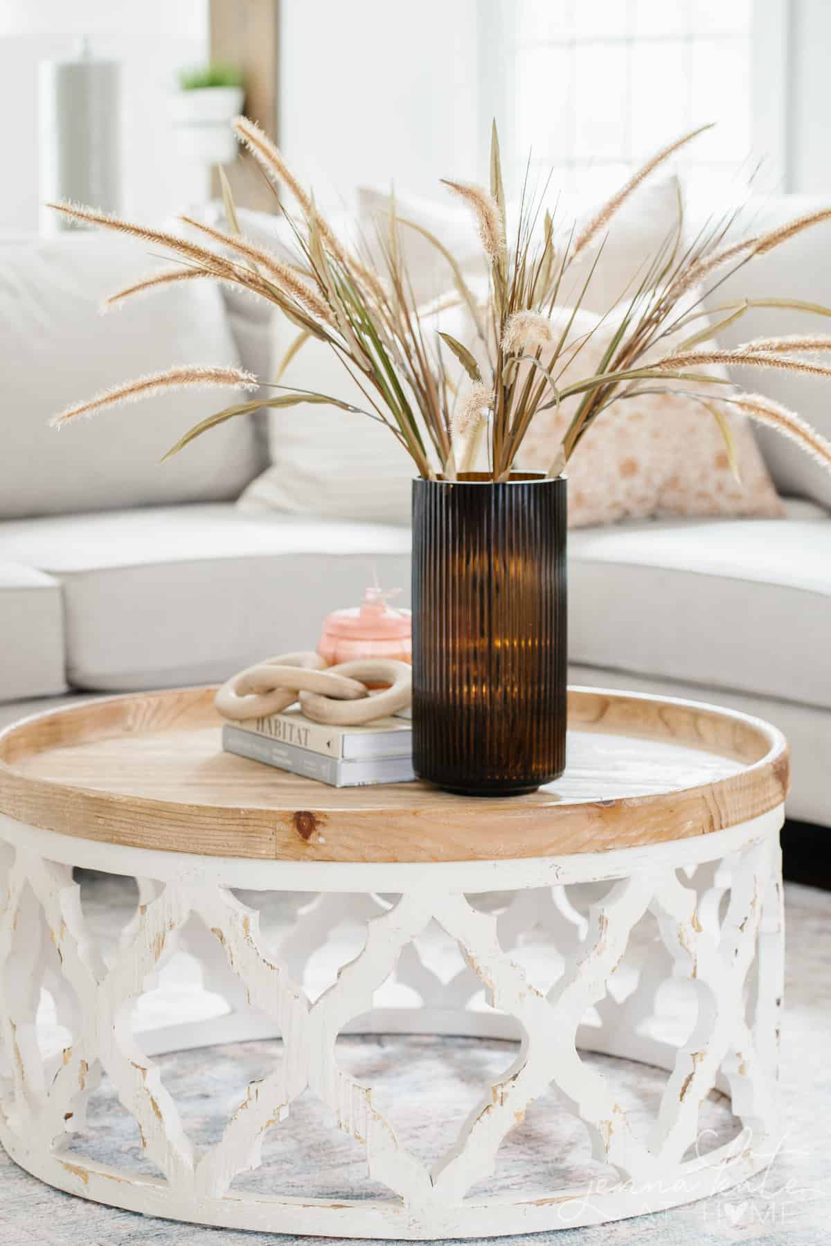 amber vase filled with dry grass on a wooden coffee table