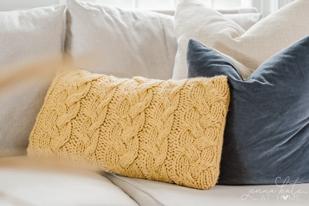 yellow cable knit pillow on a couch