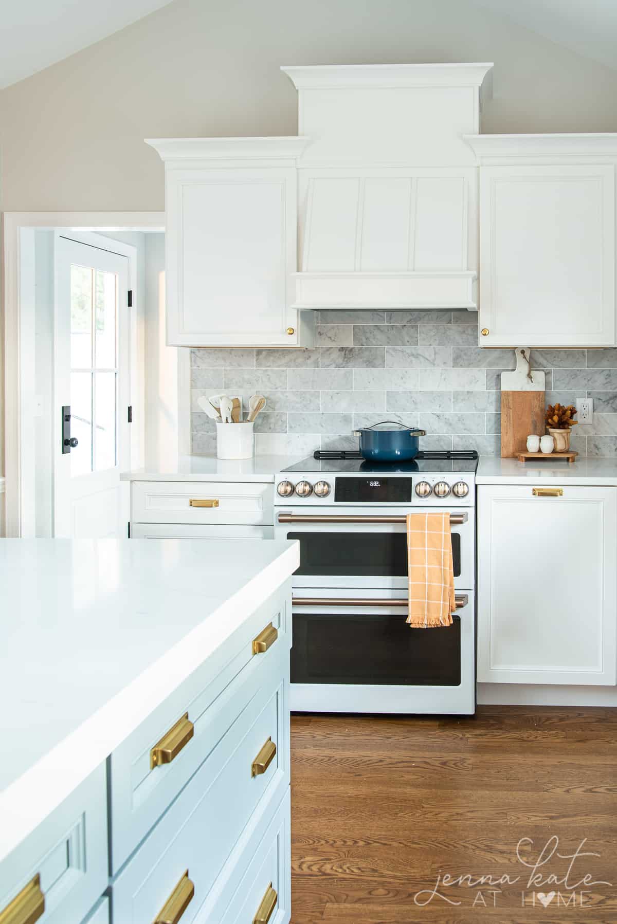 white kitchen with a mustard colored towel hanging off the stove