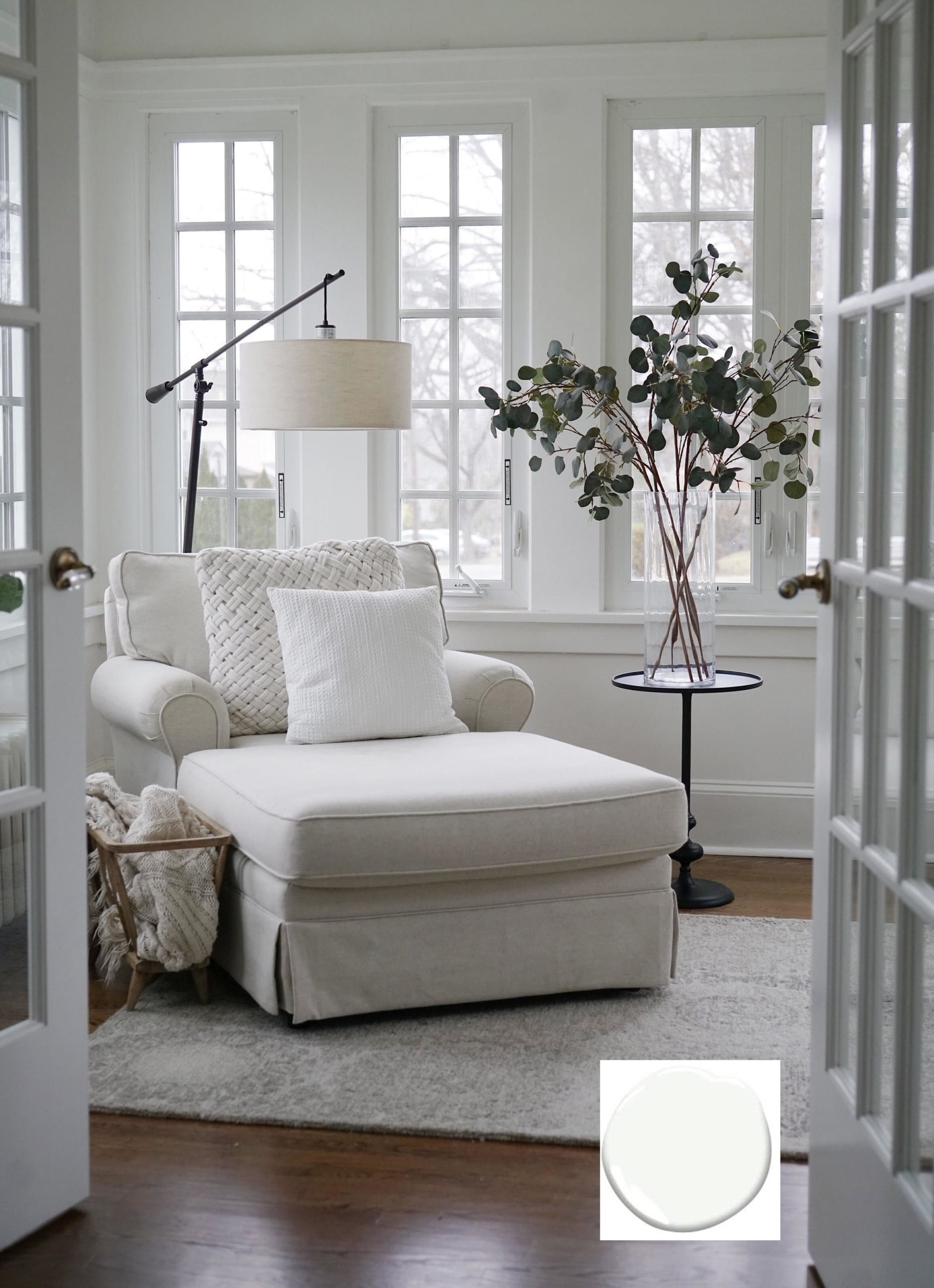 Bright living room with tons of natural light from windows that are painted with Benjamin Moore Chantilly Lace. A white comfy chair in the corner next to a lamp and side table.