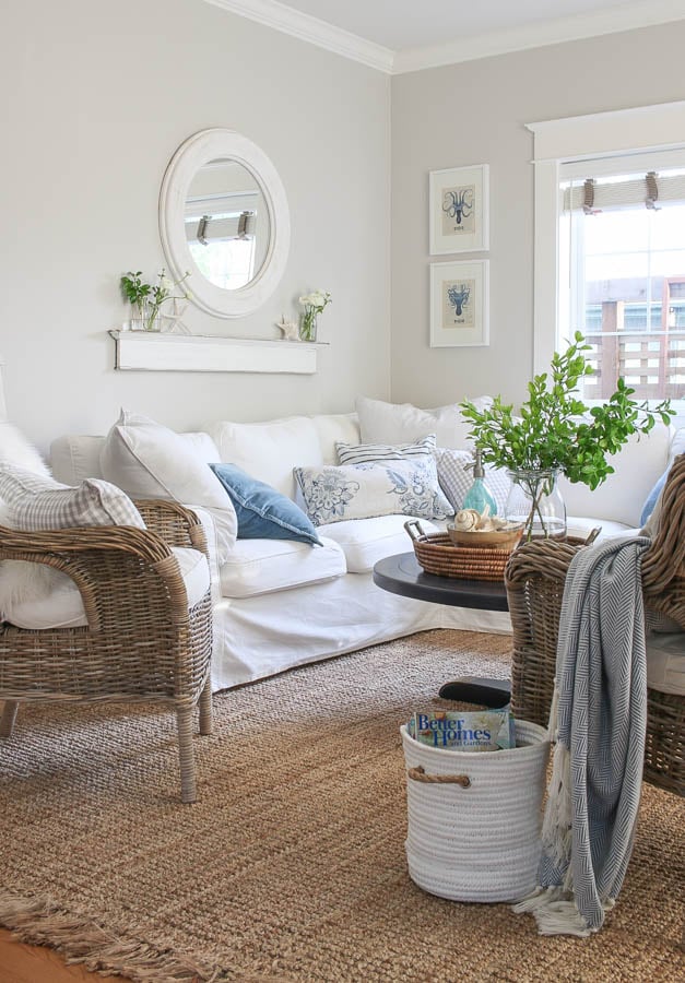 Living room with white couch, decorated coffee table, jute rug and walls painted Balboa Mist