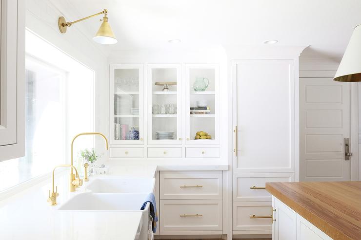 Kitchen cabinets painted with Benjamin Moore Chantilly Lace with gold hardware accents with tons of natural light shining through the window.