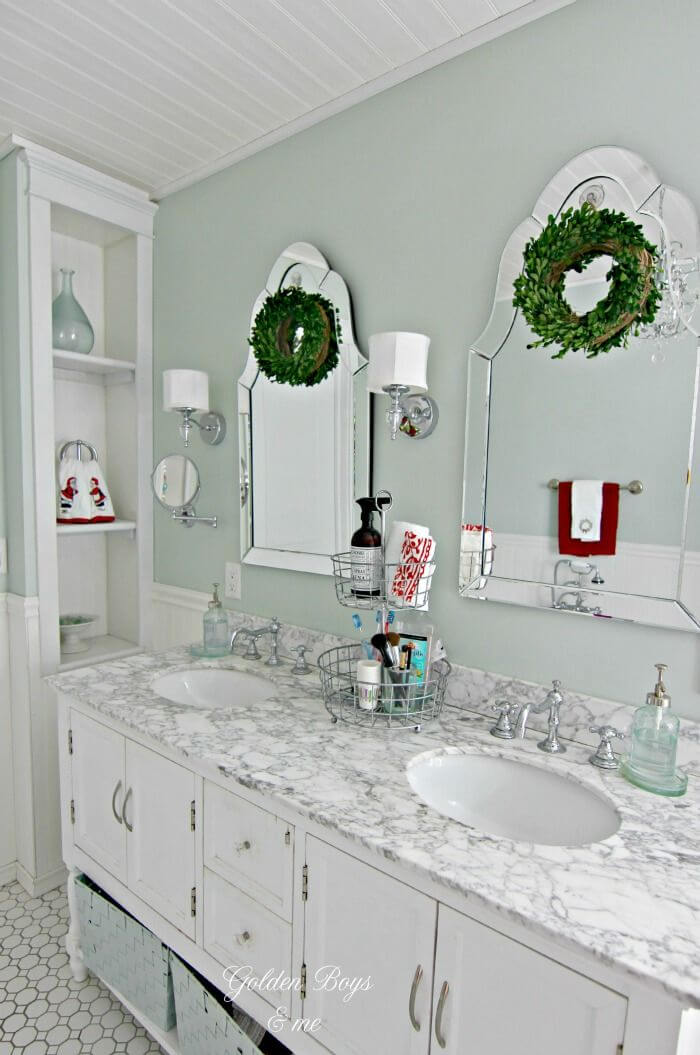 white bathroom vanity with marble top with Christmas wreaths on the mirrors