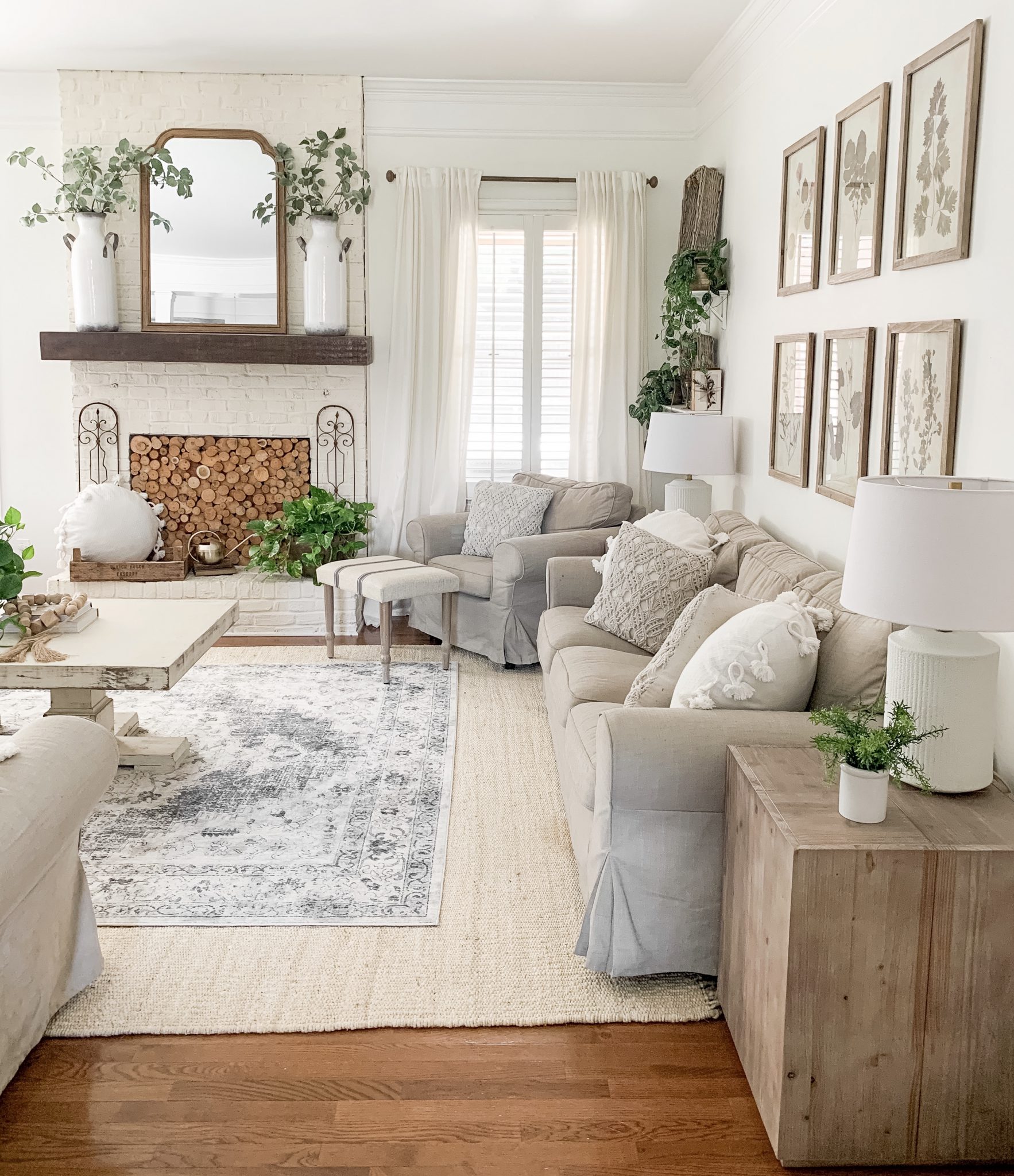 Living room with gallery wall over the couch, fireplace stacked with wood and a jute rug on the floor