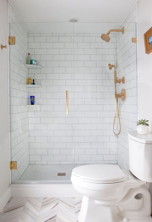 white bathroom with tiled shower and gold accent finishes