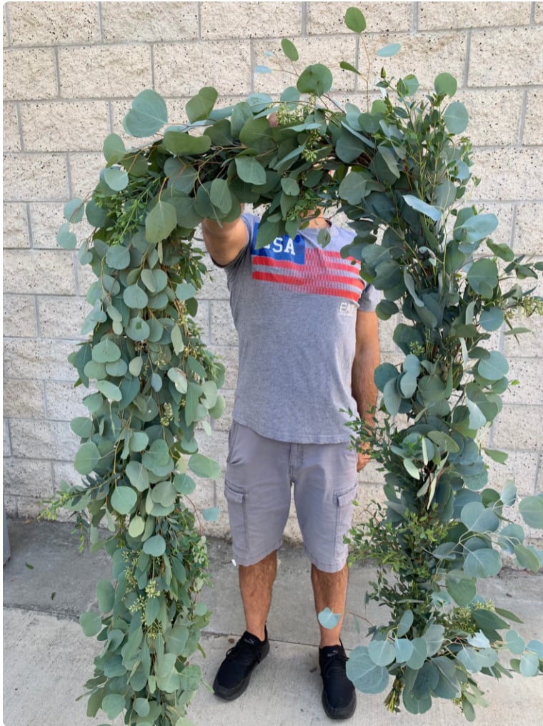 man holding a large eucalyptus garland