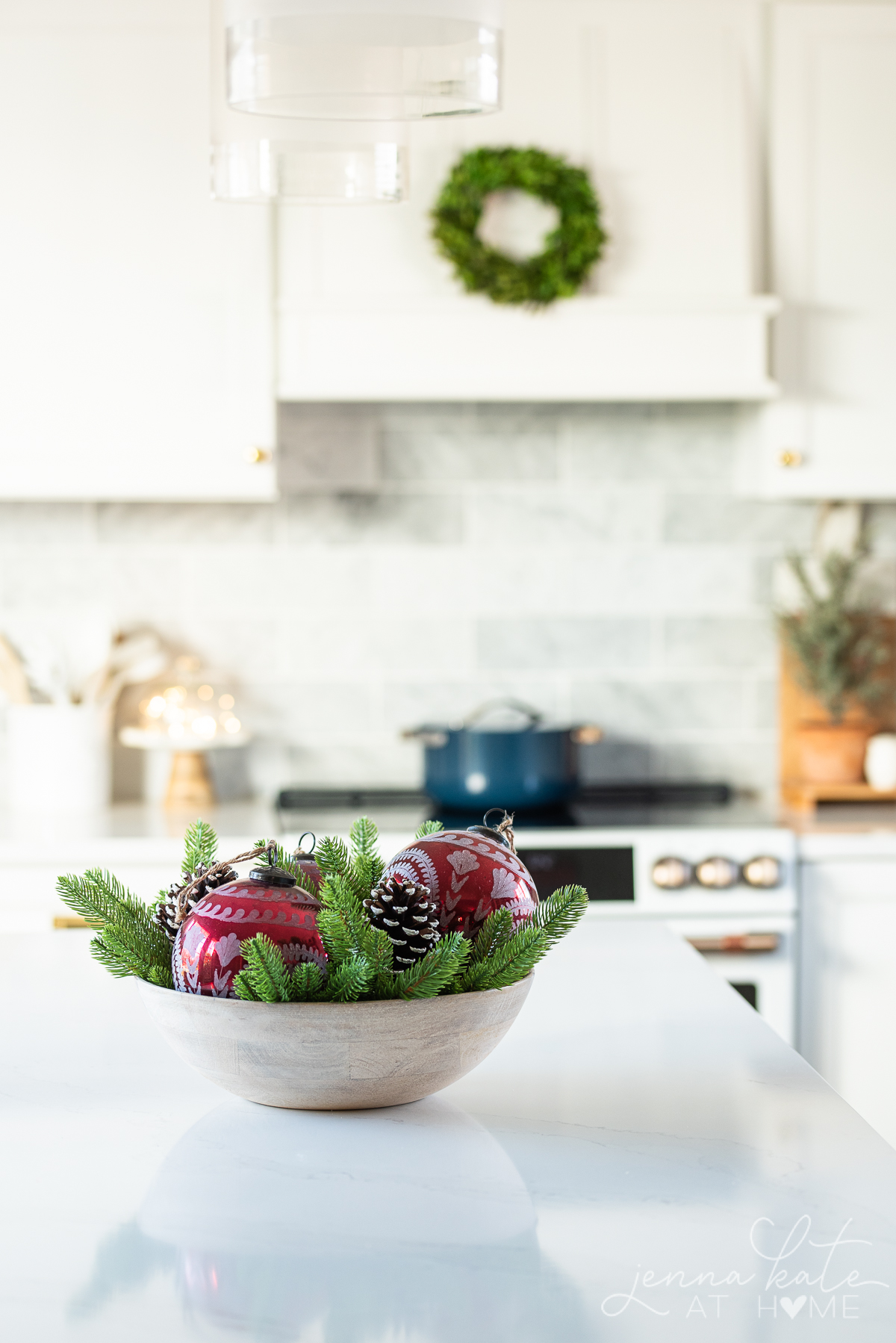bowl of ornaments on an island with a wreath hanging over the range hood