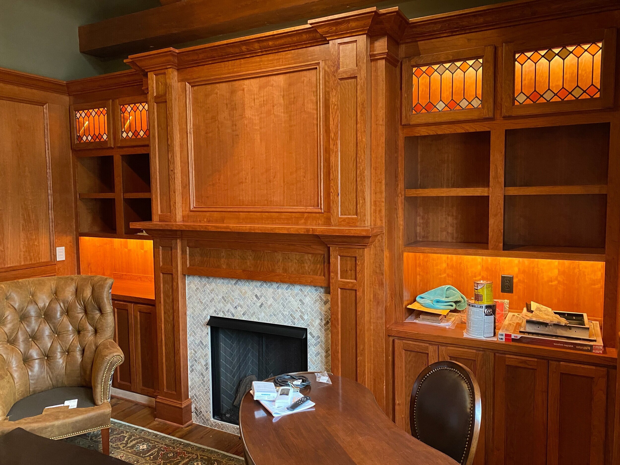 chimenea estilo shaker en tonos miel y muebles empotrados con vidrieras en los gabinetes superiores