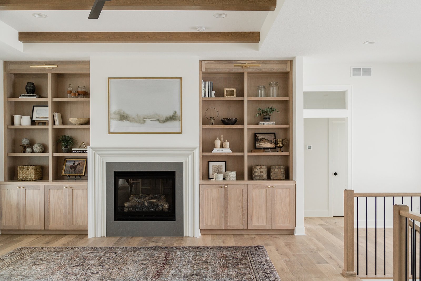 birch wood built-ins surround a white fireplace with art hanging over it