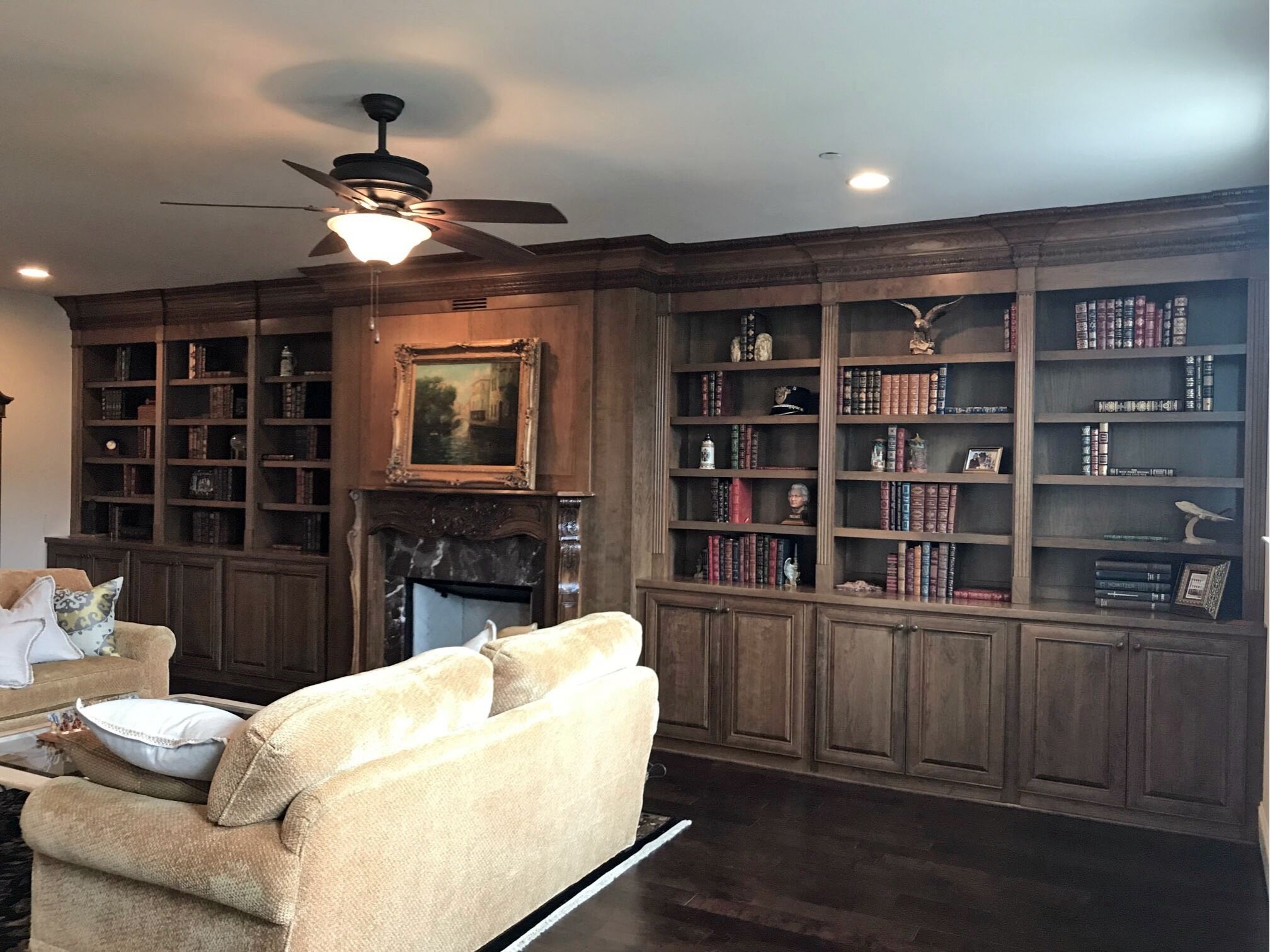 three sets of bookcases flanking each side of a rich wood fireplace