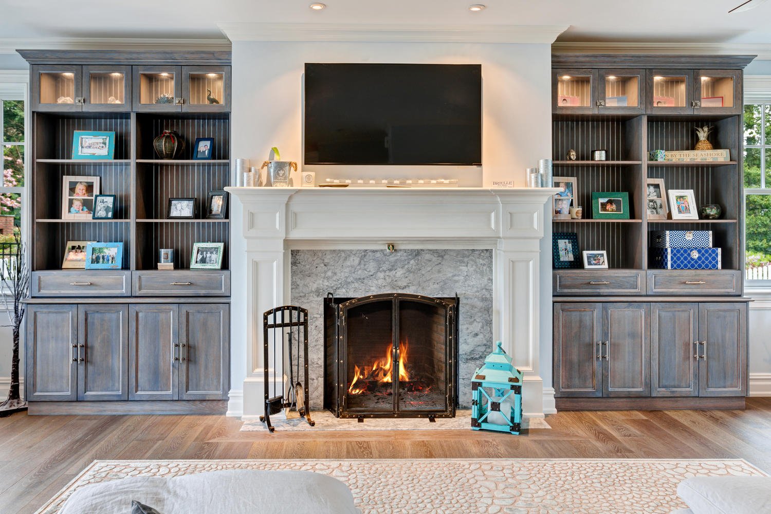 weathered look wood on built ins flanking a traditional white fireplace surround with TV over it