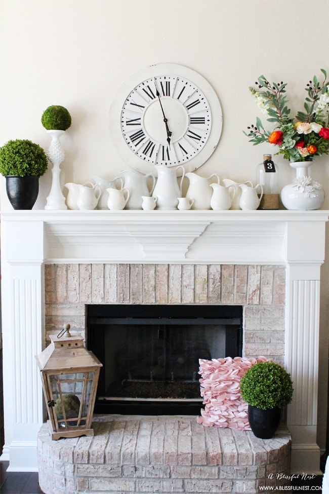 neutral spring mantel with collection of white pitchers pops of green and colorful bouquet