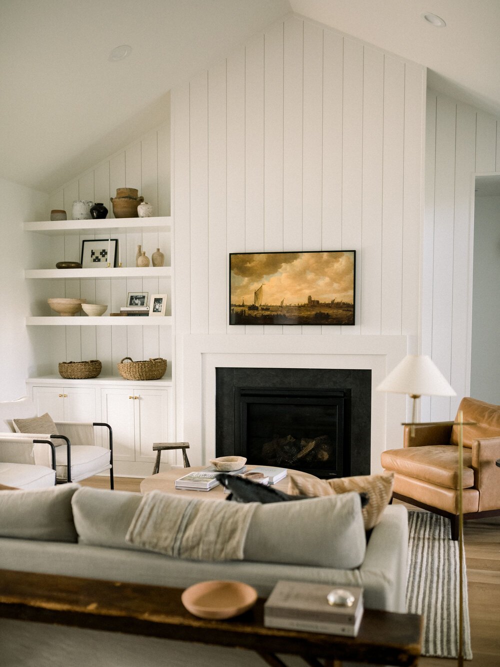 simple white fireplace with built-ins on one side and vertical shiplap background that goes to the ceiling