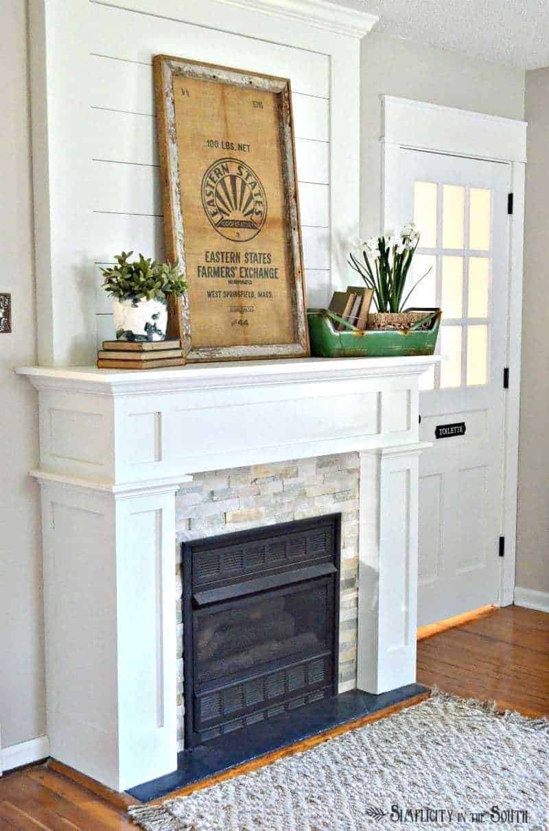 white mantle with pops of greenery and vintage framed flour sack
